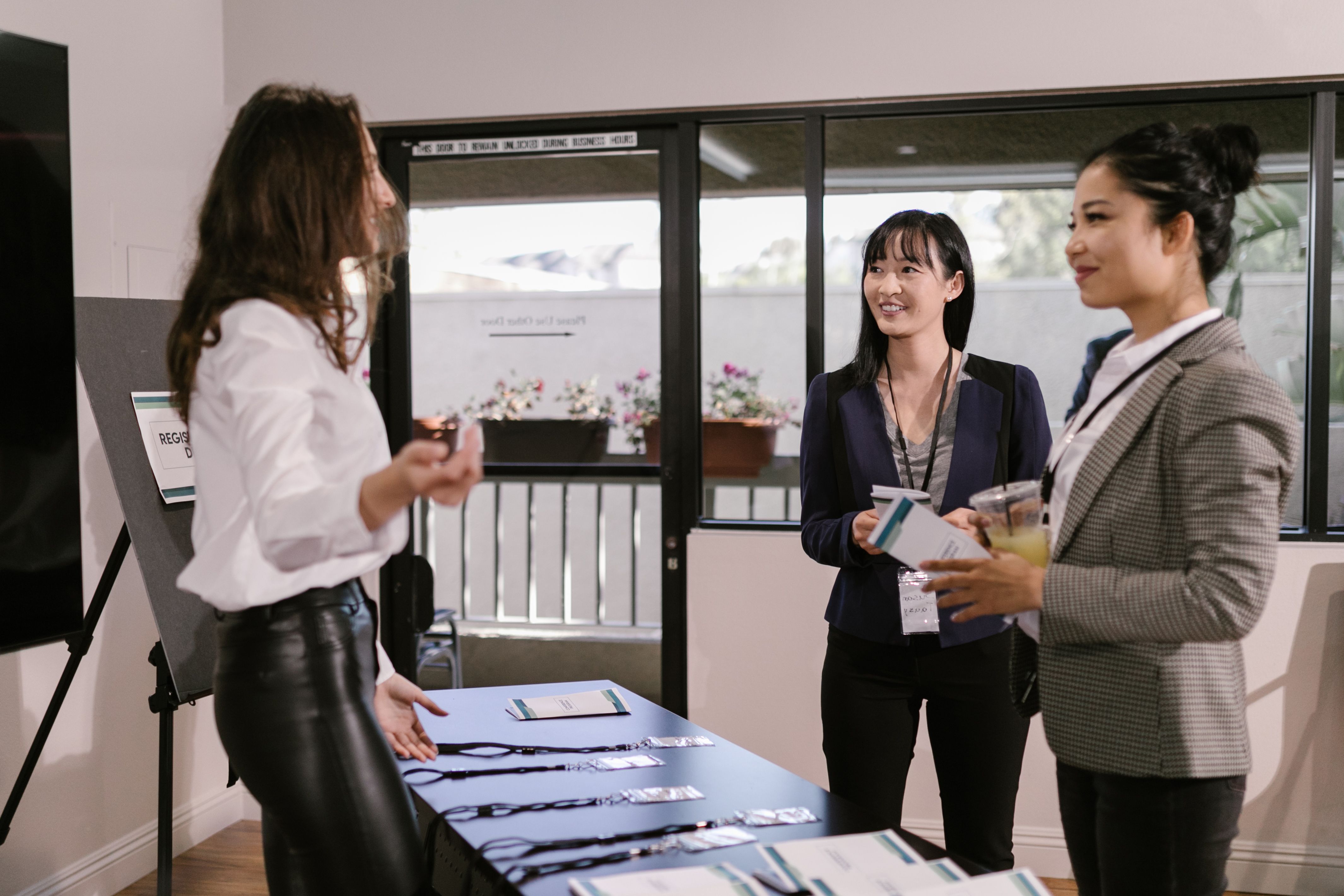 Recepcionistas conferindo credenciamento de participantes numa mesa de check-in em evento corporativo