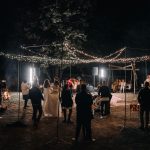 Recepção de casamento à noite com convidados e luzes decorativas