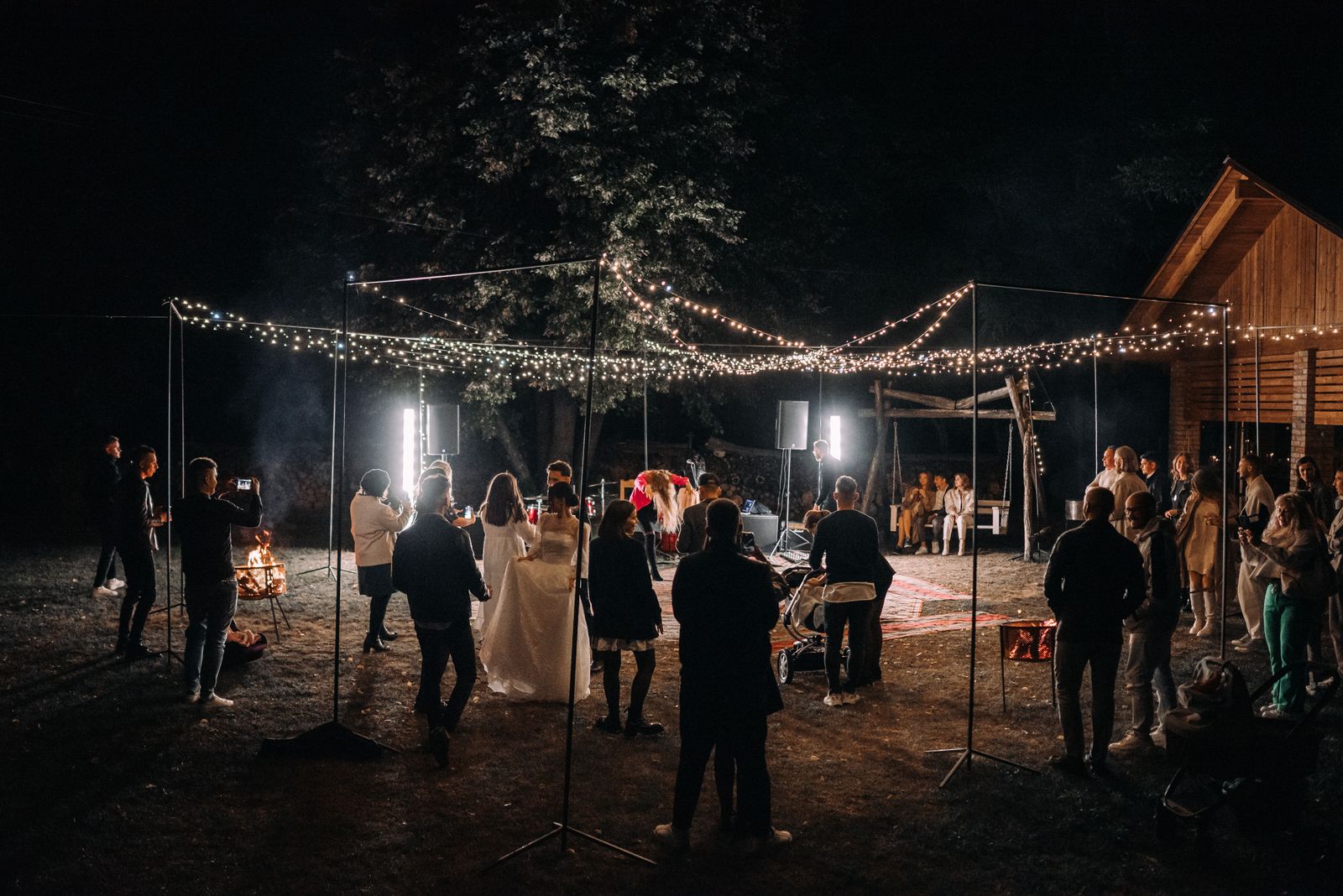 Recepção de casamento à noite com convidados e luzes decorativas
