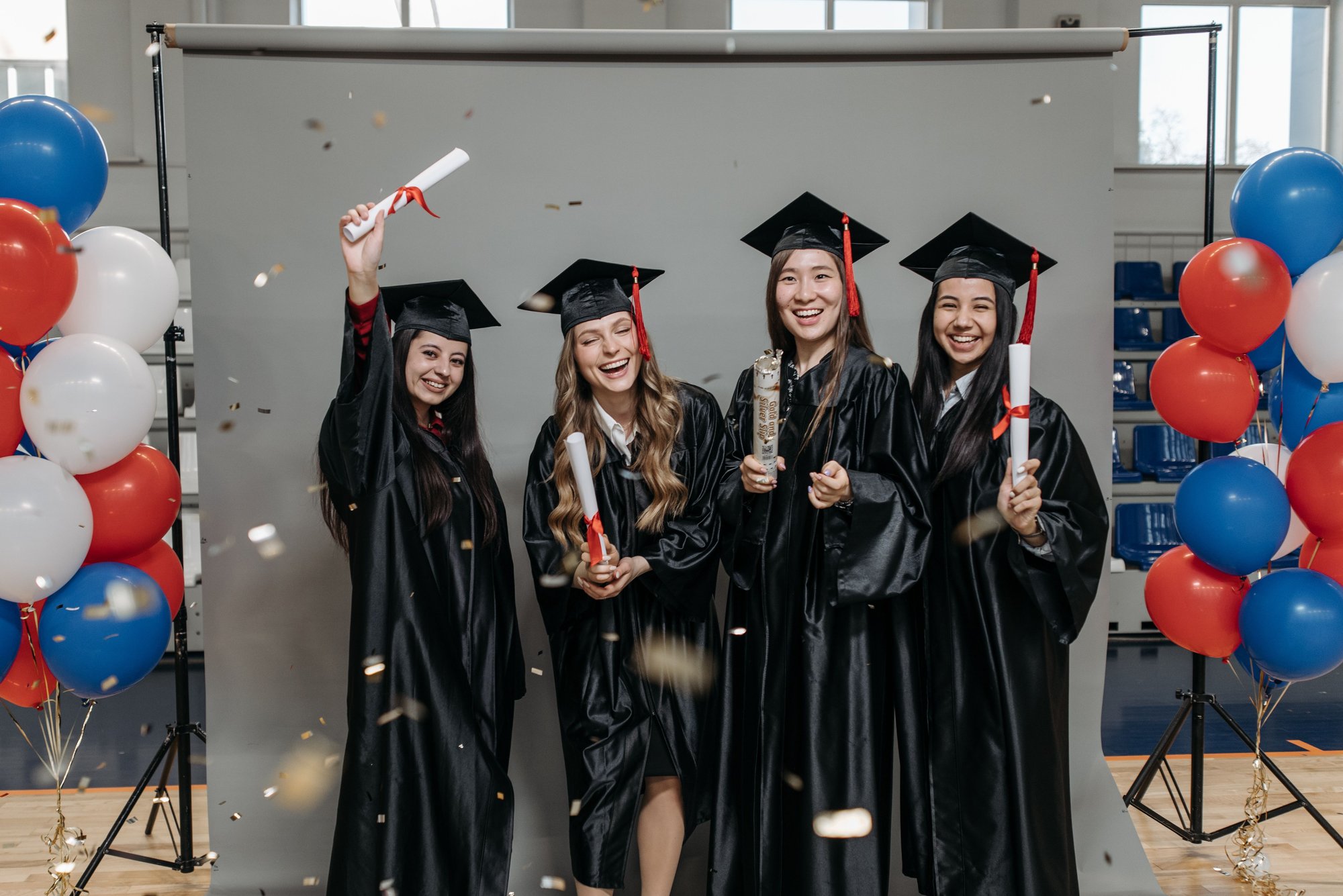 Formandas comemorando a formatura com beca, capelo e diploma nas mãos