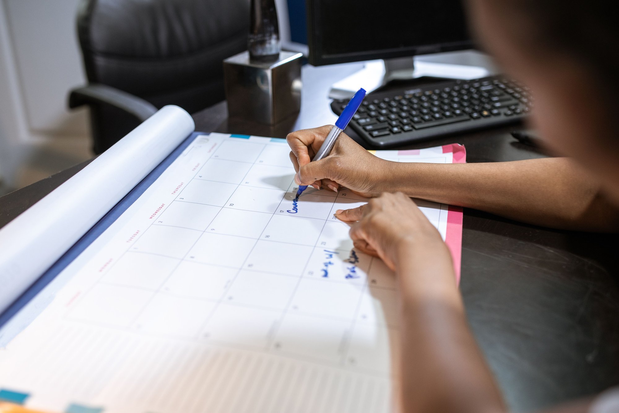 Profissional de eventos marcando prazo de confirmação de presença em calendário de mesa