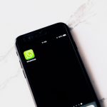 Smartphone sobre mesa branca exibindo o aplicativo WhatsApp, representando a confirmação de presença via WhatsApp Business