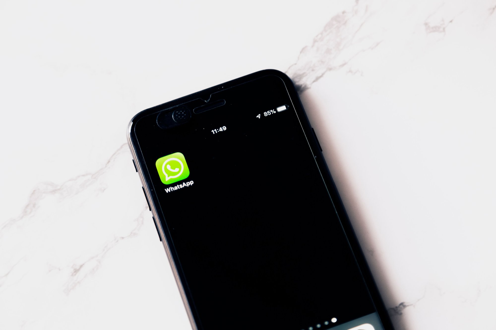 Smartphone sobre mesa branca exibindo o aplicativo WhatsApp, representando a confirmação de presença via WhatsApp Business