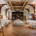Salão de casamento montado com mesas redondas e cadeiras vazias e mapa de mesas na entrada