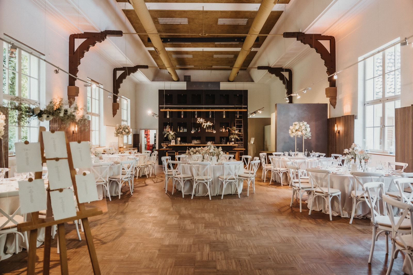 Salão de casamento montado com mesas redondas e cadeiras vazias e mapa de mesas na entrada